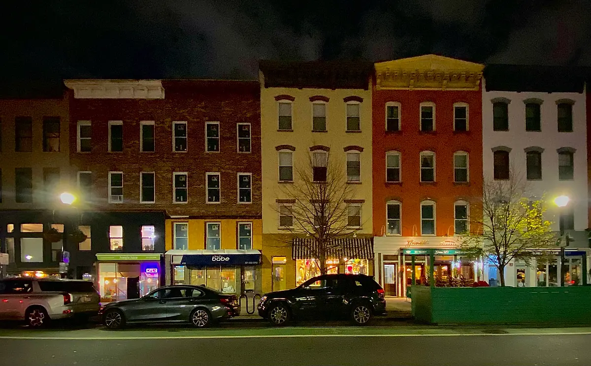 Washington Street rowhouses at night in Hoboken, with lit shopfronts