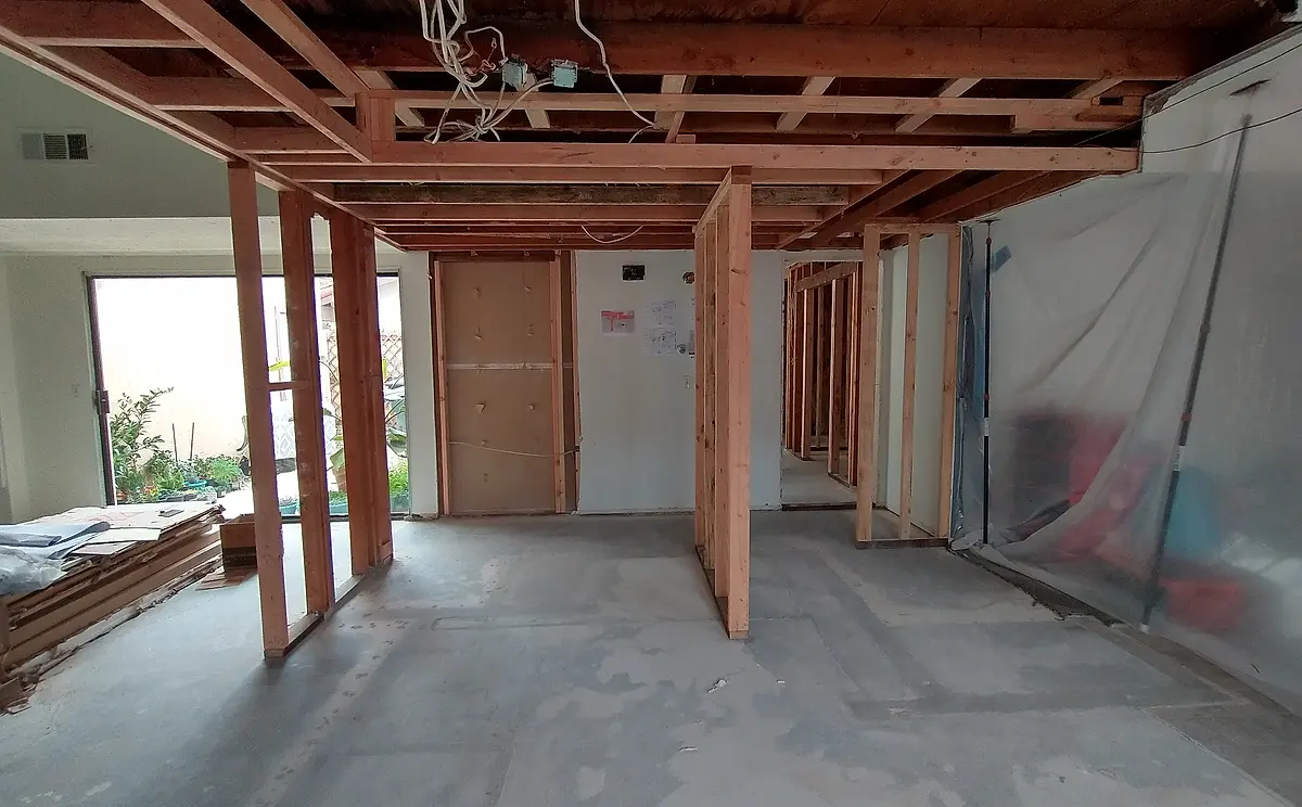 A kitchen gutted to the studs mid-renovation, new framing and open ceiling joists