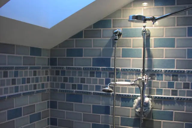 A blue-tiled shower under a skylight with two shower heads
